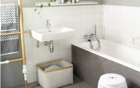 Renovated bathroom - sink and bathtub against half-height tiled wall below walls painted pale grey